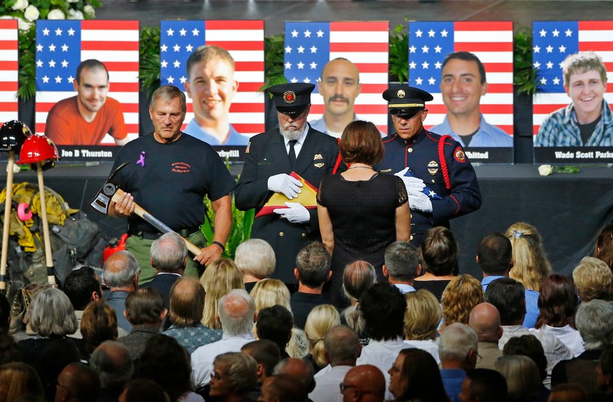 An honor guard presents families with an American flag during a memorial service in Prescott Valley, Arizona, Tuesday, July 9, 2013, for the 19 Granite Mountain hotshot firefighters that were killed while battling the Yarnell Hill Fire.