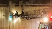 Fire engulfs aerial ladder with firefighter on tip