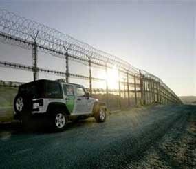A U.S. Border Patrol vehicle guards the border fence with its concertino wire topping in San Diego. The "virtual border fence" will be used to compliment some physical fencing already in place, and in some cases, there will be no visible fencing at all. (AP Photo)