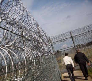 Deputy Warden of Security Keith Eutsey, left, and Warden Bruce Chatman walk to the execution chamber along rows of barbed wire at the Georgia Diagnostic and Classification Prison, Tuesday, Dec. 1, 2015, in Jackson, Ga.