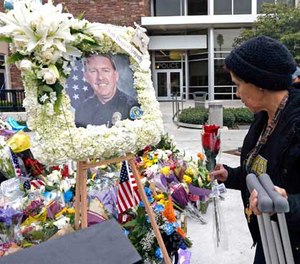 Theresa Mendoza, a formerly homeless woman who knew Whittier Police Officer Keith Boyer, adds a rose to a growing memorial for the fallen hero.